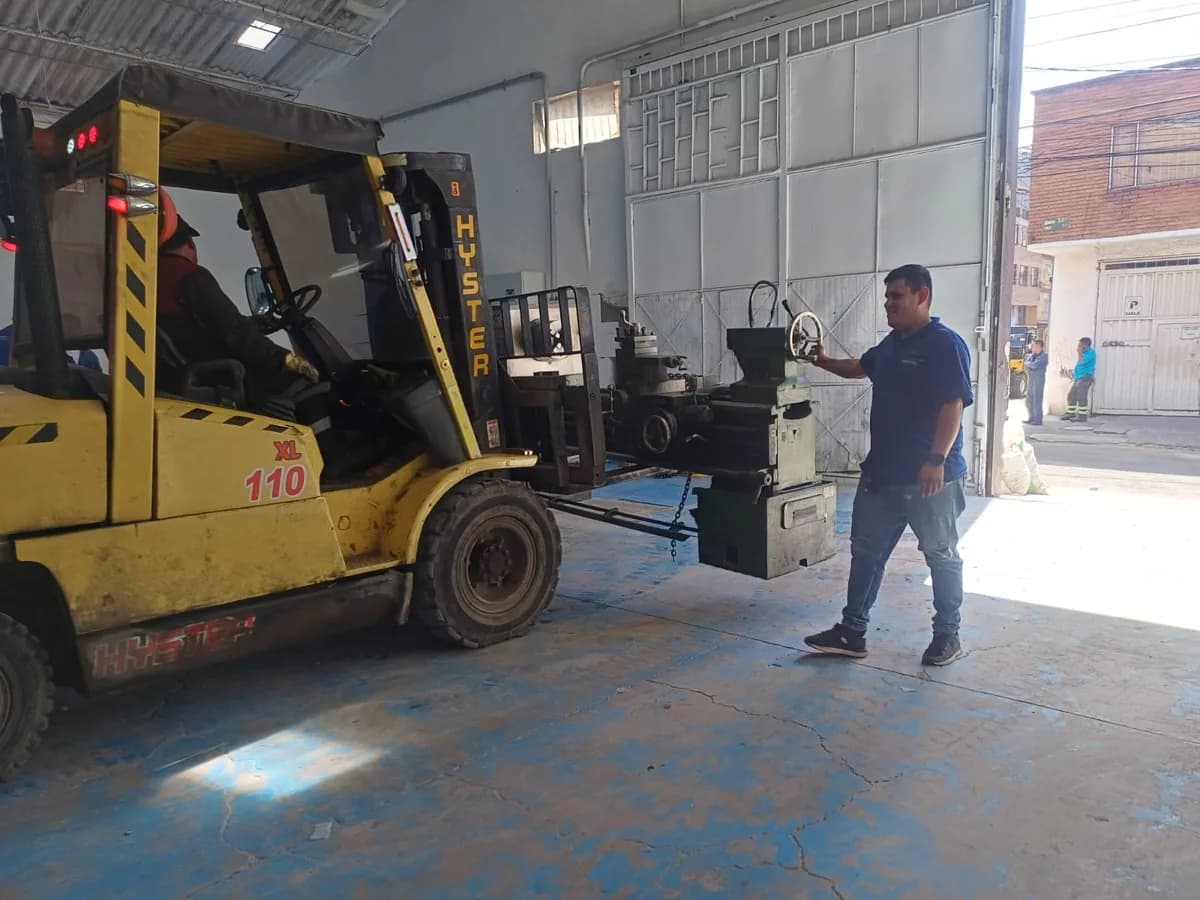 Montacargas manipulando maquinaria industrial en bodega